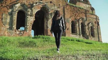 linda garota atlética caminhando ao longo dos antigos edifícios em ruínas. câmera lenta. atirando na steadicam video