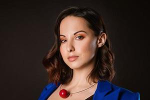A business woman in a blue jacket poses for the camera on a dark background photo