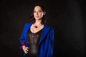 A business woman in a blue jacket poses for the camera on a dark background photo