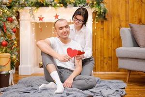 Couple in love, man and woman in white t-shirts, holding wooden red hearts photo