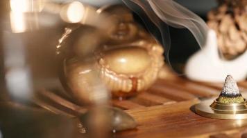 Pyramide aus duftendem Wacholder glimmt auf dem Hintergrund der Teefigur. schöne Teezeremonie. Entspannung und Aromatherapie. Zeitlupe. FullHD-Aufnahmen in hoher Qualität