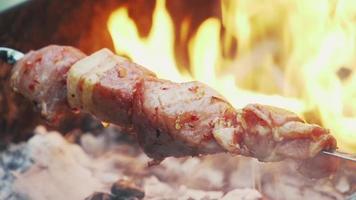 Kochen von Kebab auf dem Grill in der Nähe. Lagerfeuer und gebraten das Fleisch auf den Spießen. Picknick. leckeres Essen. Zeitlupe video
