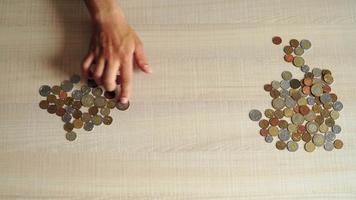 young man sits at table at home and recalculates coins. concept financial crisis and poverty. Top view. Close up video