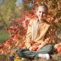 niña en el heno con calabazas foto