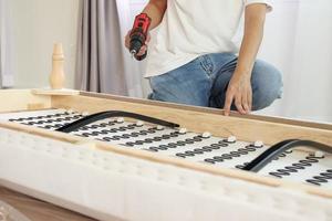 man assembling sofa furniture at home using cordless screwdriver photo