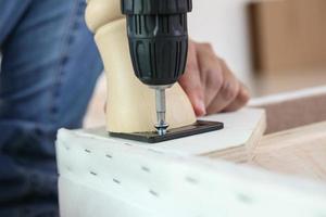 man assembling sofa furniture at home using cordless screwdriver photo