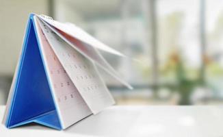 white paper desk calendar on wood table with blurred bokeh background appointment and business meeting concept photo