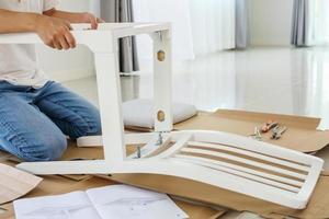 Man assembling white chair furniture at home photo