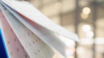 Close up white paper desk calendar with blurred bokeh background appointment and business meeting concept photo