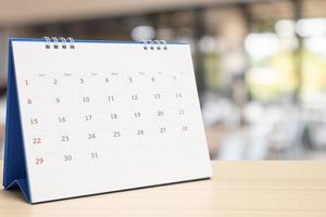 white paper desk calendar on wood table with blurred bokeh background appointment and business meeting concept photo