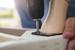 man assembling sofa furniture at home using cordless screwdriver photo