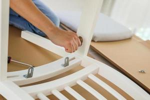 Man assembling white chair furniture at home photo