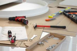 Cordless screwdriver and tool on cardboard paper assembly furniture concept photo