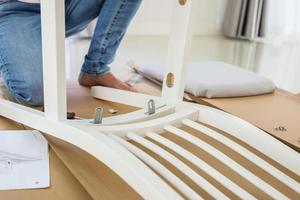 Man assembling white chair furniture at home photo