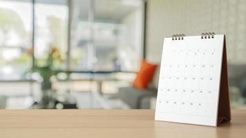 white paper desk calendar on wood table with blurred bokeh background appointment and business meeting concept photo