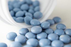 Píldoras de medicina azul con botella sobre fondo blanco. foto