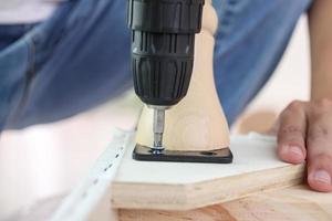 man assembling sofa furniture at home using cordless screwdriver photo