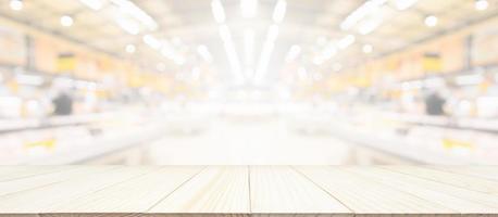 mesa de madera con fondo borroso de la tienda de comestibles del supermercado con luz bokeh para la exhibición del producto foto