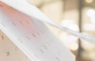 Close up white paper desk calendar with blurred bokeh background appointment and business meeting concept photo