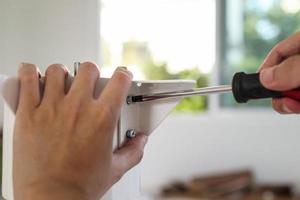 hombre asiático montando muebles de mesa blanca en casa foto