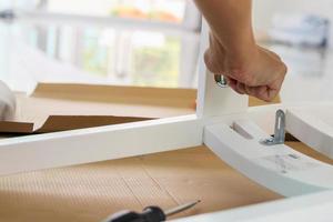 Man assembling white chair furniture at home photo