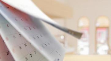 Close up white paper desk calendar with blurred bokeh background appointment and business meeting concept photo