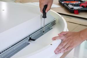 Asian man assembling white table furniture at home photo