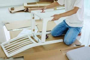 hombre montando muebles de silla blanca en casa foto