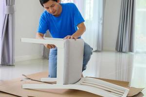 hombre montando muebles de silla blanca en casa foto