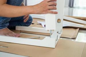 Man assembling white chair furniture at home photo