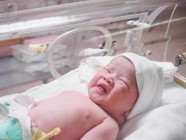 Newborn baby inside incubator in hospital post delivery room photo
