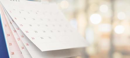 Close up white paper desk calendar with blurred bokeh background appointment and business meeting concept photo