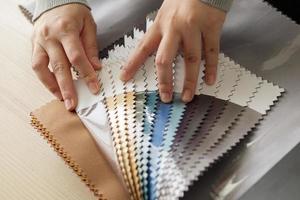 diseñadora femenina con muestras de color de tela eligiendo textiles para cortinas foto