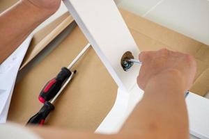 Man assembling white chair furniture at home photo