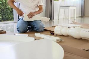 Man assembling white table furniture at home photo