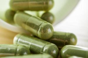 Herbal medicine capsules with bottle on wood table photo