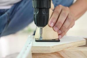 man assembling sofa furniture at home using cordless screwdriver photo