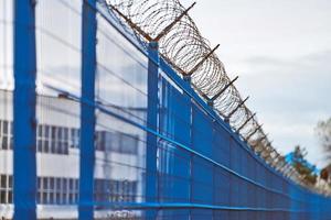 Barbed wire on blue fence of restricted area photo