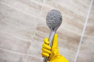 Female hand holds shower head with pouring water, copy space photo