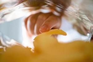 recogiendo papas fritas a mano dentro de una bolsa de bocadillos foto