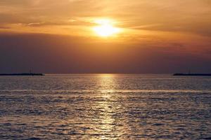 mar tranquilo con cielo de puesta de sol, hermosa vista panorámica, increíble y espectacular sol naciente reflejado en el agua foto