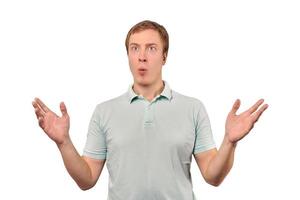 Confused young guy shrugged shoulders, guy in casual T-shirt spread arms isolated white background photo