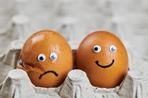 Funny egg and sad cracked egg in paper egg tray photo