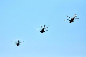 Three military helicopters flying in blue sky performing demonstration flight, air show, copy space photo