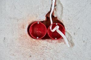 Plastic socket box and electrical wires on plastered wall photo