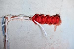 cajas de enchufe de plástico y cables eléctricos en la pared enyesada foto