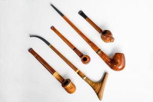 A top view of various wooden smoking pipes on a white background photo