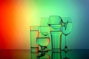 Some glasses for different drinks stacked on a colorful background photo