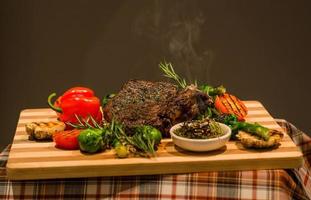 Closeup of serving table for lunch, fried meat, vegetables, green pepper and grilled potatoes on wooden board photo