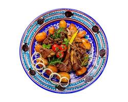 A top view of a national Uzbek dish with meat and potatoes served in a plate with traditional patterns photo